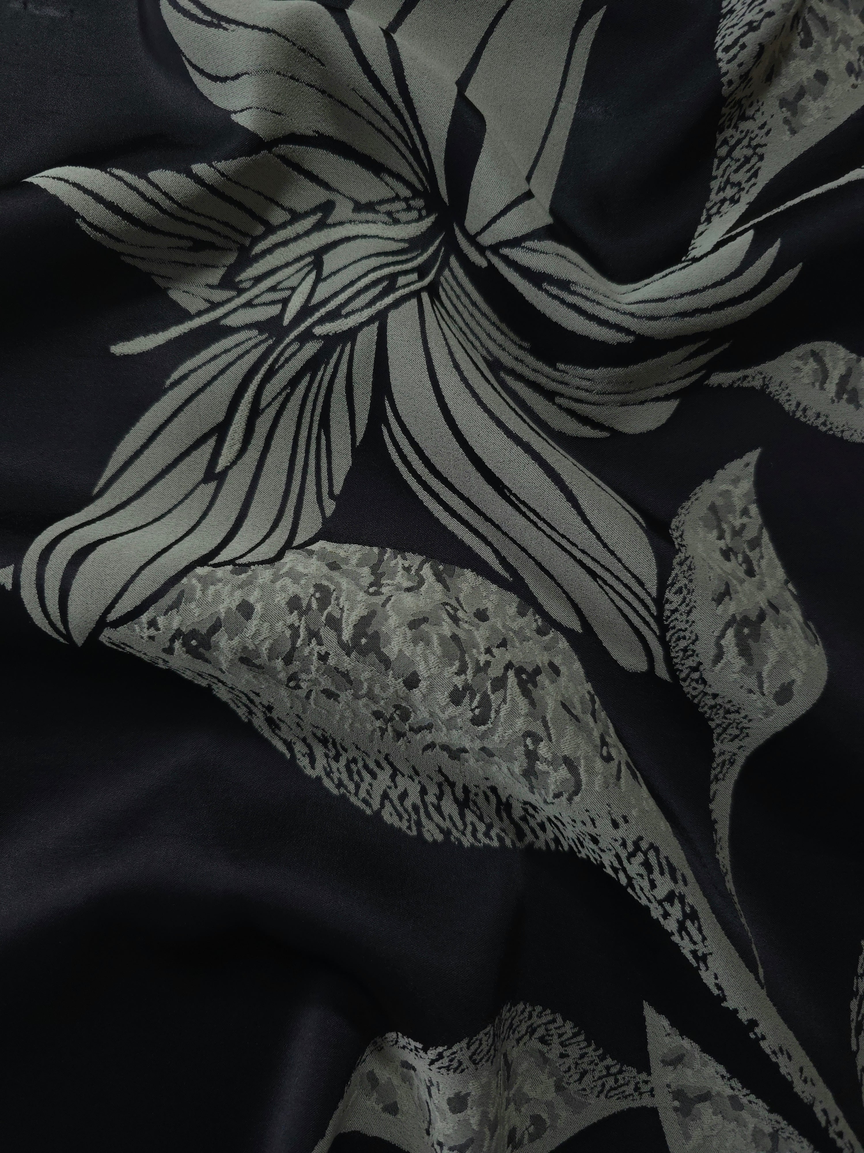 Black satin folded softly, the sage lily flower line art reading crisply against the deep base