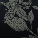 A wider view of the black and sage lily flower satin laid flat, showing the full line-art repeat