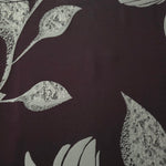 A wider section of the plum and sage lily flower satin, shown to judge the textured floral pattern at scale