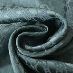 A tight fold in the teal-green satin, the lattice rows bending with the crease of the fabric