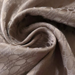 A soft crease in the taupe-bronze satin, the lattice rows catching light unevenly at the fold