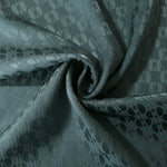 Teal-green lattice satin draped to catch the light, the geometric texture visible across the fold