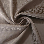 Taupe-bronze lattice satin draped loosely, the geometric texture visible across the moving fabric