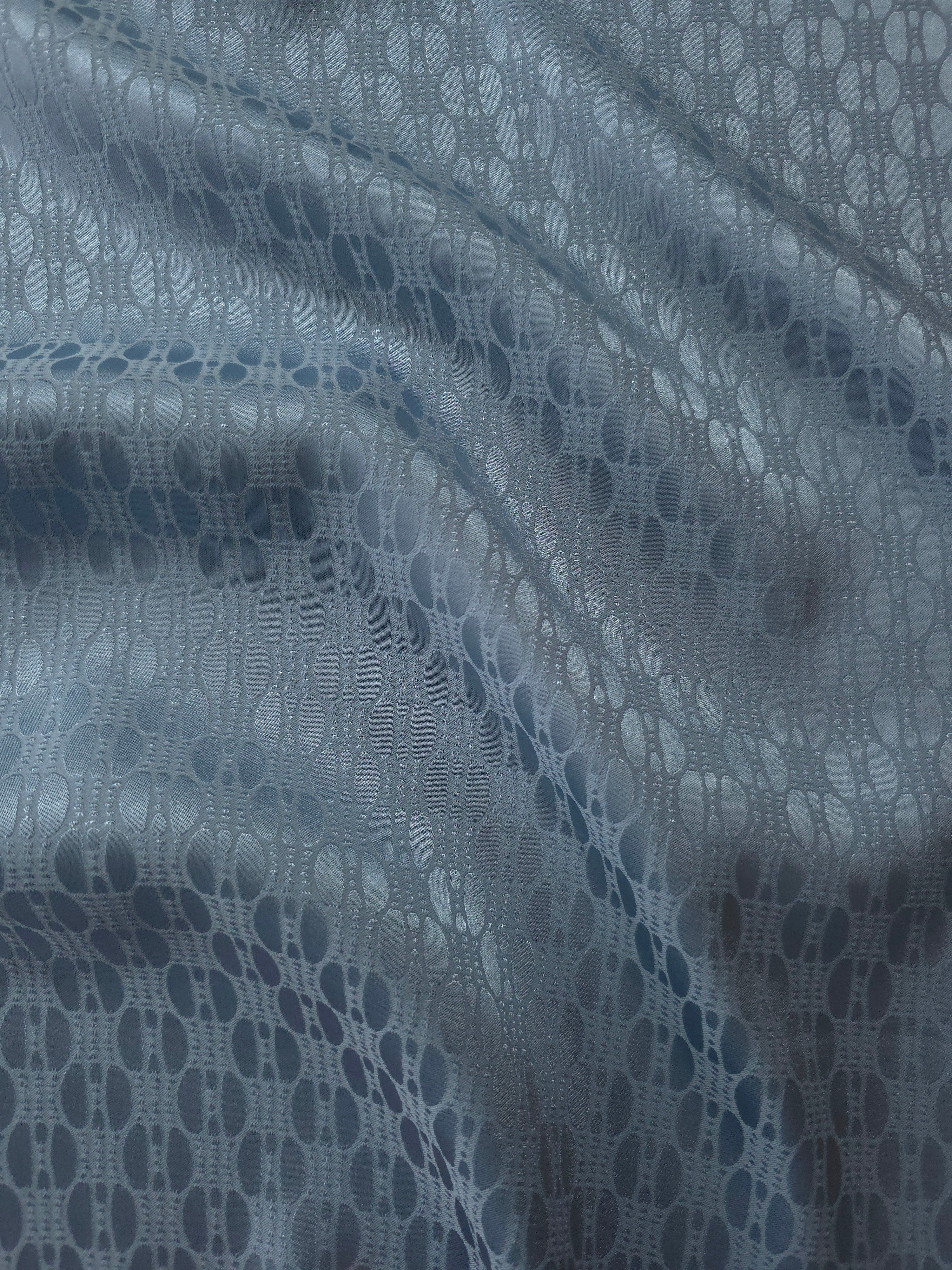 Slate blue satin folded over, the repeating oval lattice pattern reading as a structured geometric texture