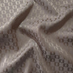 Taupe-bronze satin folded softly, the same oval lattice pattern reading warmer than the slate blue colorway