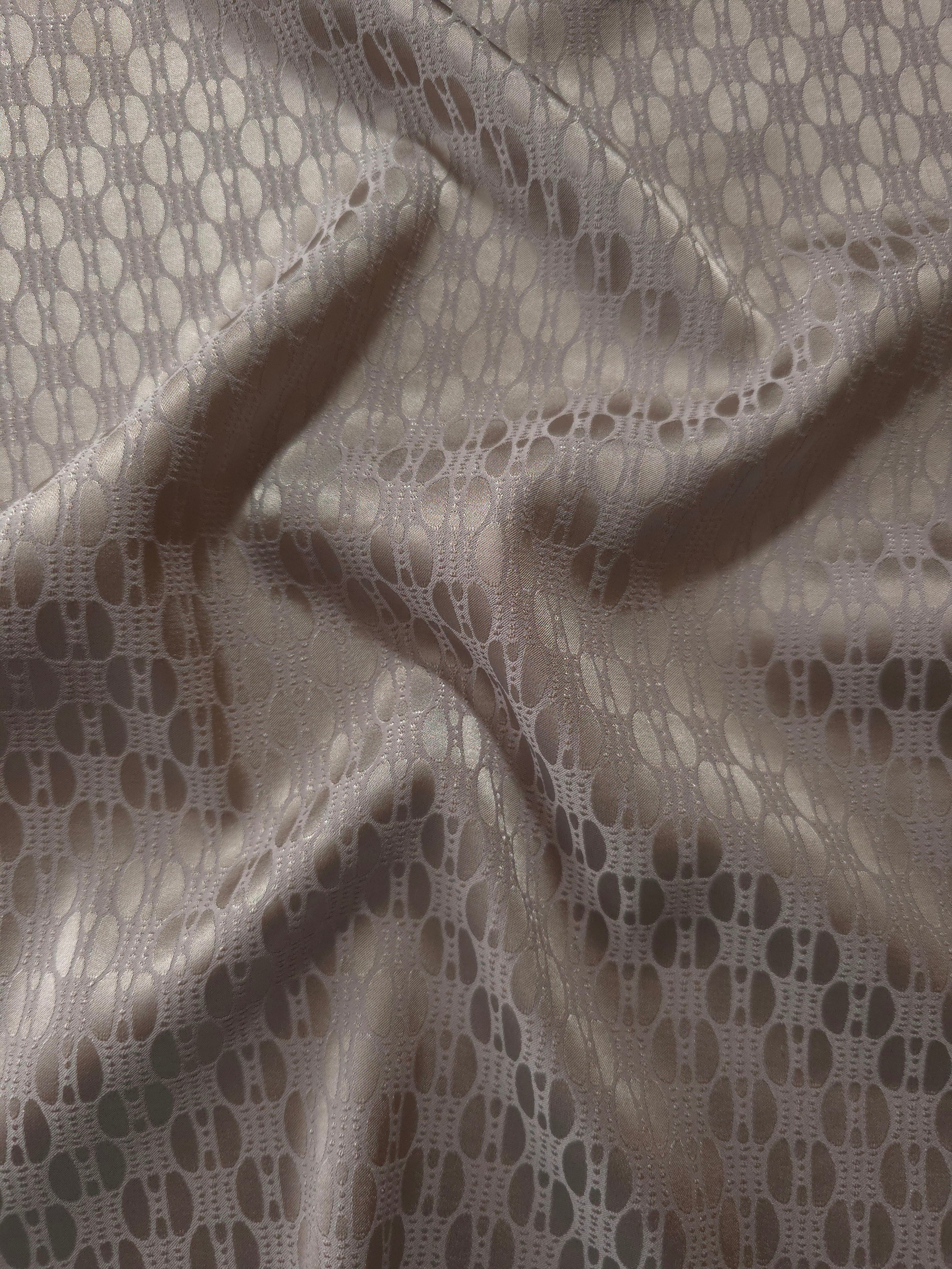 Taupe-bronze satin folded softly, the same oval lattice pattern reading warmer than the slate blue colorway