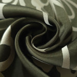 A soft crease in the forest green satin, the flower silhouette breaking across the fold