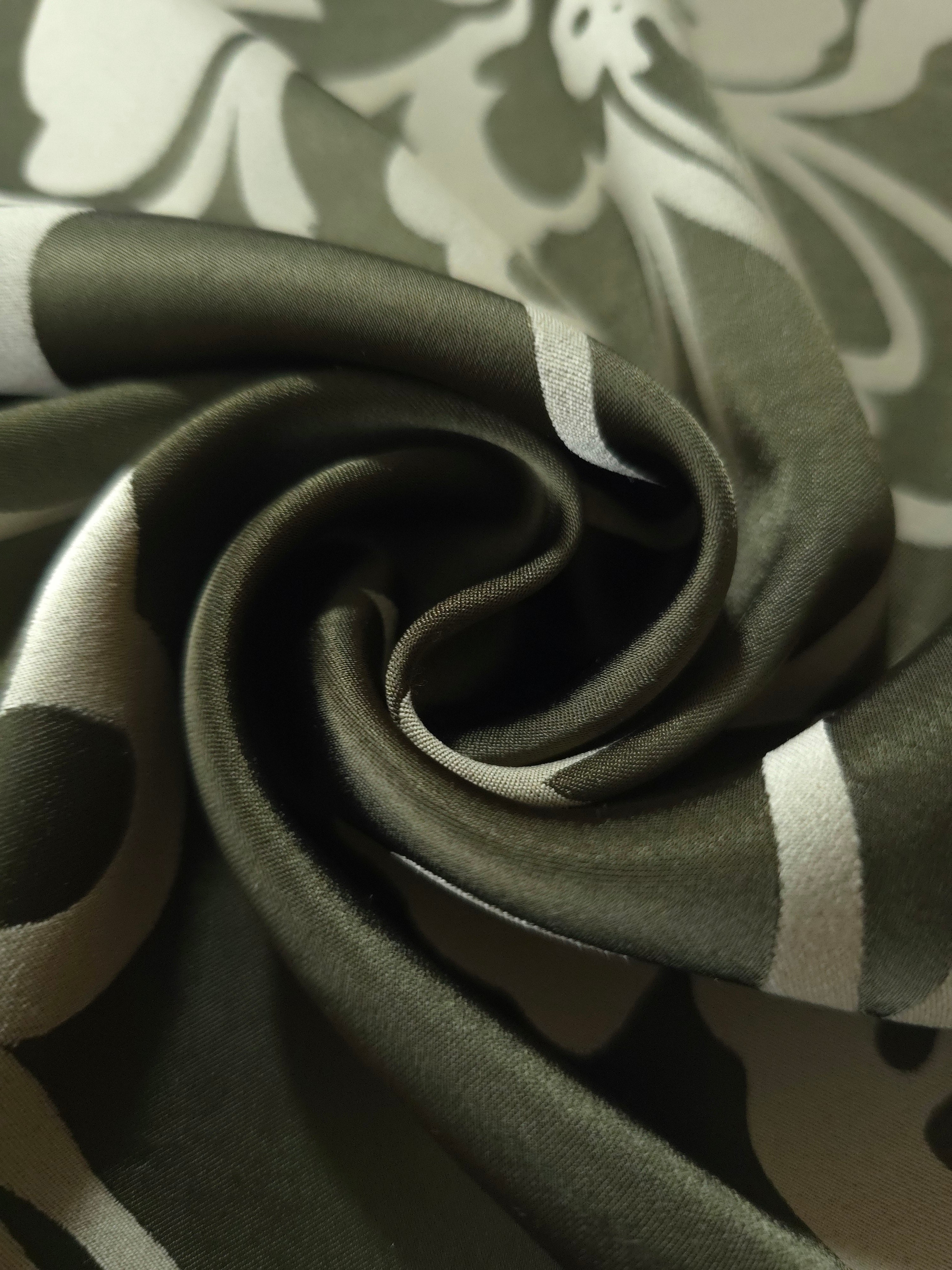 A soft crease in the forest green satin, the flower silhouette breaking across the fold