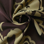 Aubergine pansy flower satin draped to catch the light, the bold petal silhouette visible across the fold