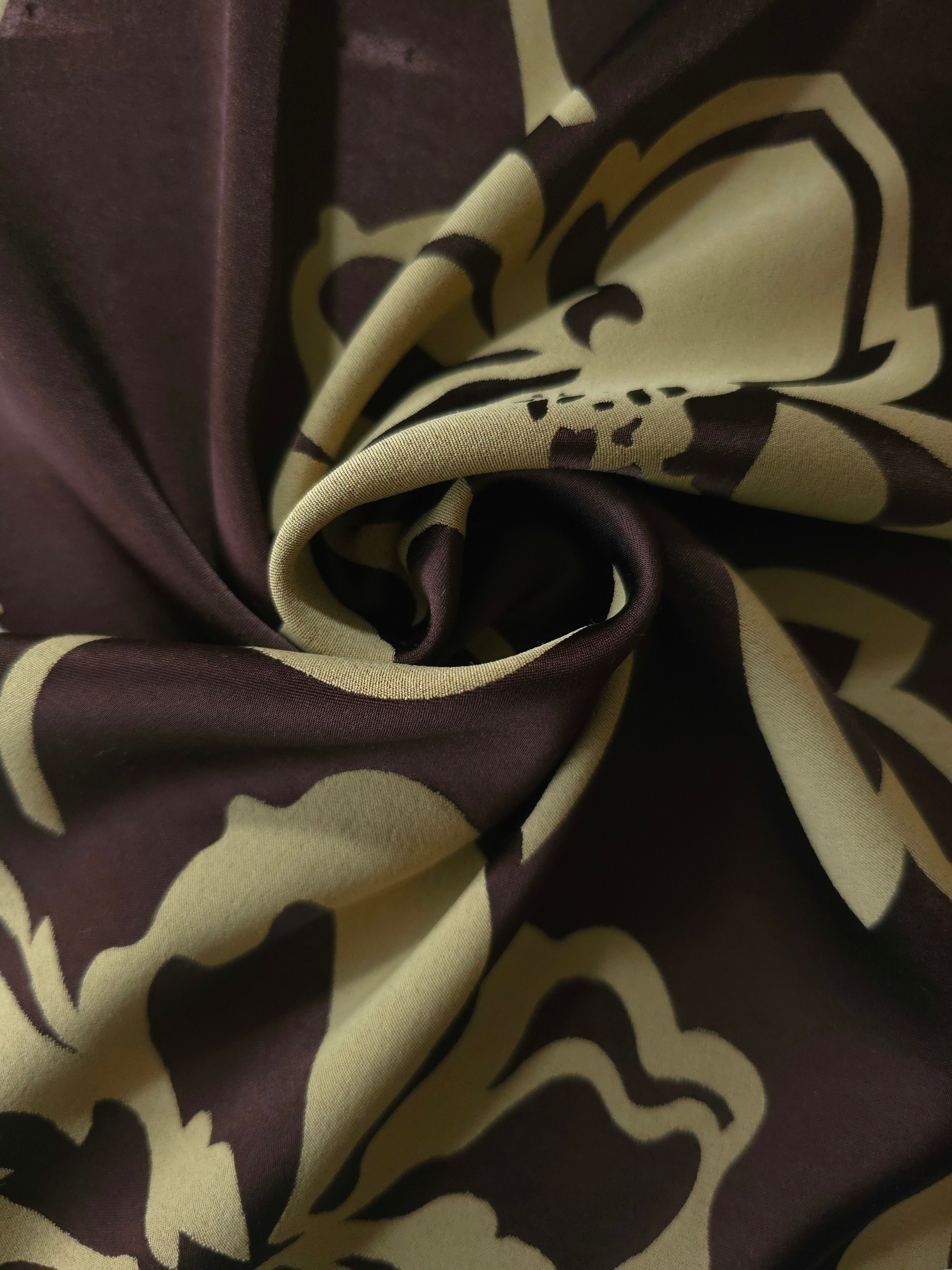 Aubergine pansy flower satin draped to catch the light, the bold petal silhouette visible across the fold