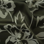 Forest green satin folded softly, the pale sage flower outline reading sharply against the darker base
