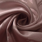 Fabric pinched into soft folds, showing how the dusty rose tone holds together even where the satin creases
