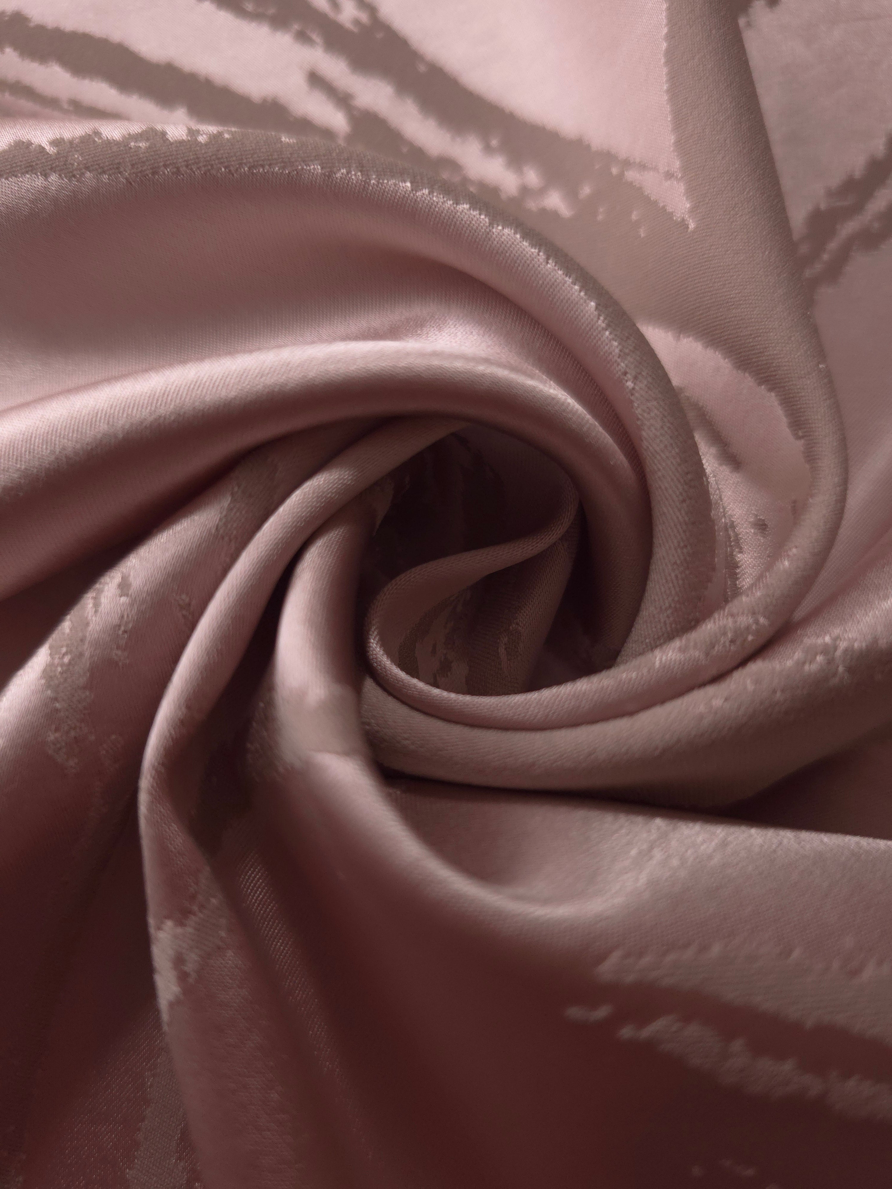 Fabric pinched into soft folds, showing how the dusty rose tone holds together even where the satin creases