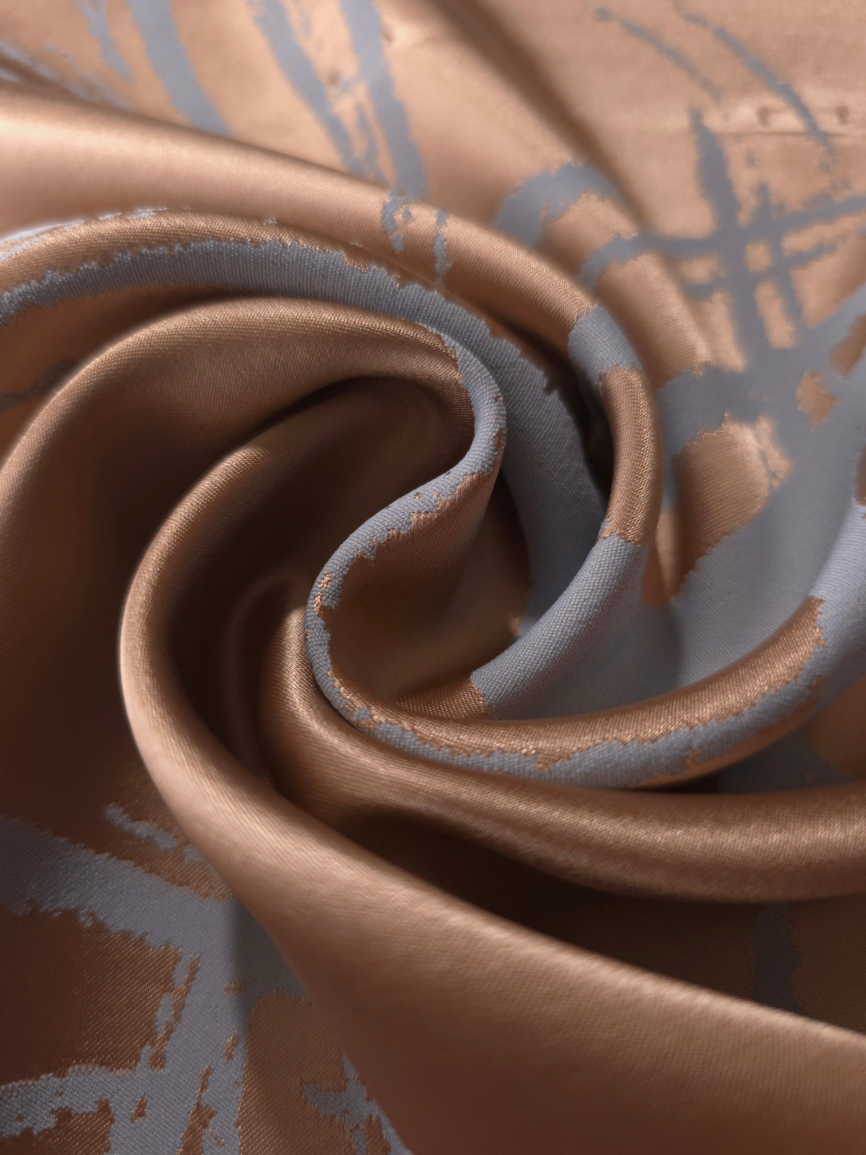 Copper satin pinched into a tight fold, showing how the blue-grey lines hold their shape even where the fabric creases