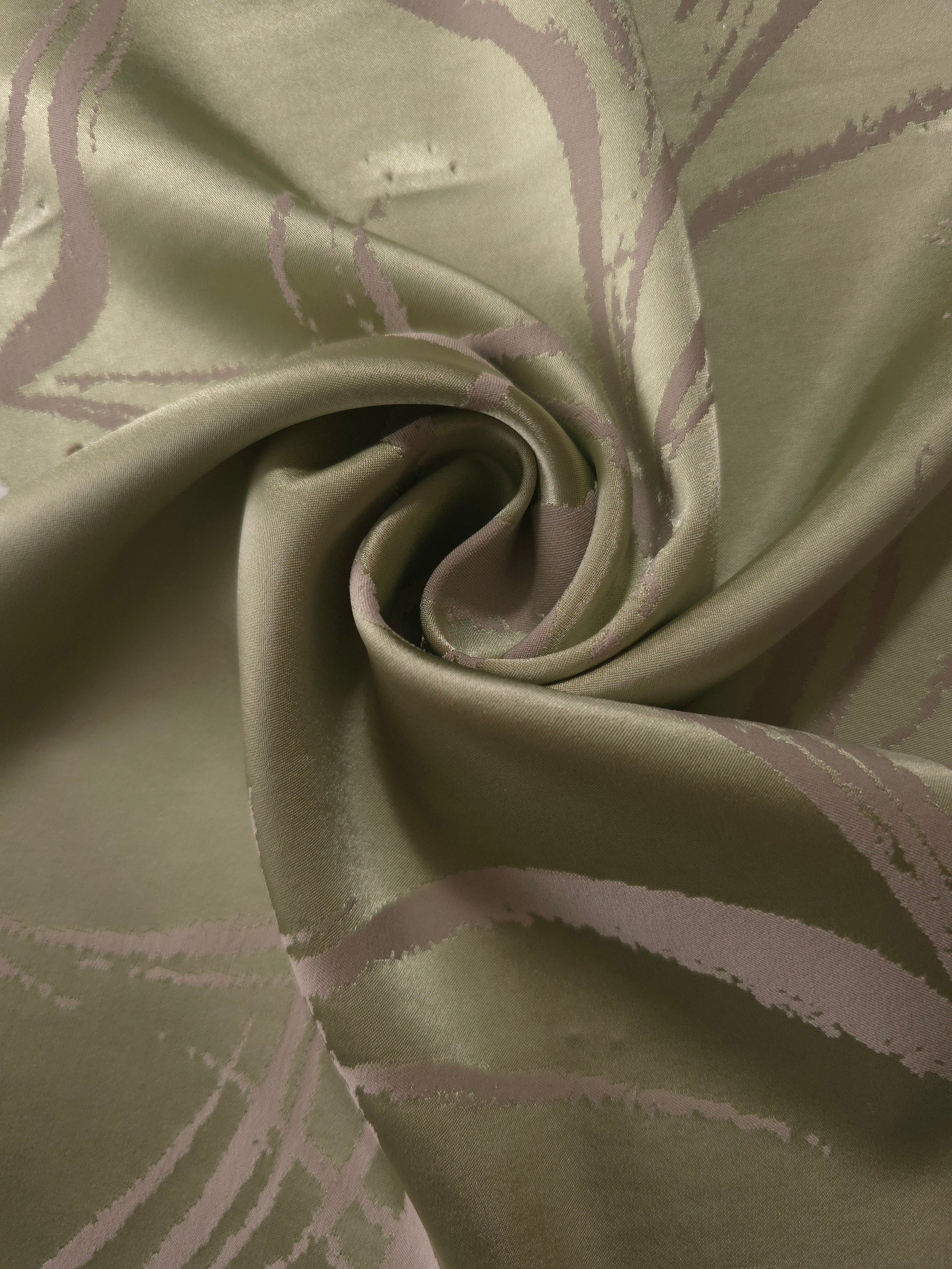 Sage green Lassi satin draped to show its fluid movement, the seaweed lines visible across the curve of the fold