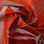 Orange-red seaweed satin draped to catch the light, the high-contrast lines visible across the moving fabric