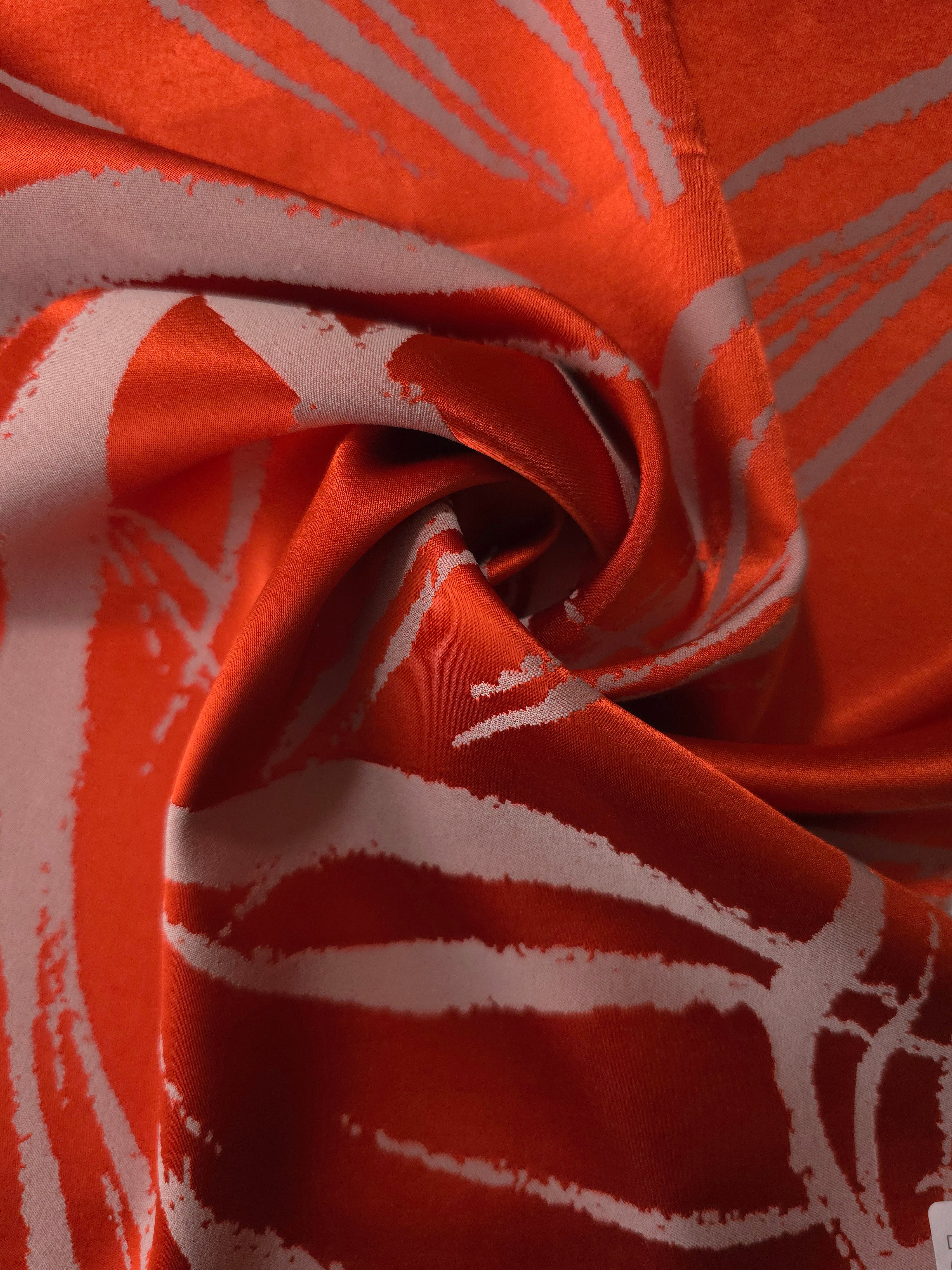 Orange-red seaweed satin draped to catch the light, the high-contrast lines visible across the moving fabric