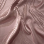 Dusty rose Lassi satin folded to show how the seaweed motif catches light differently across each curve