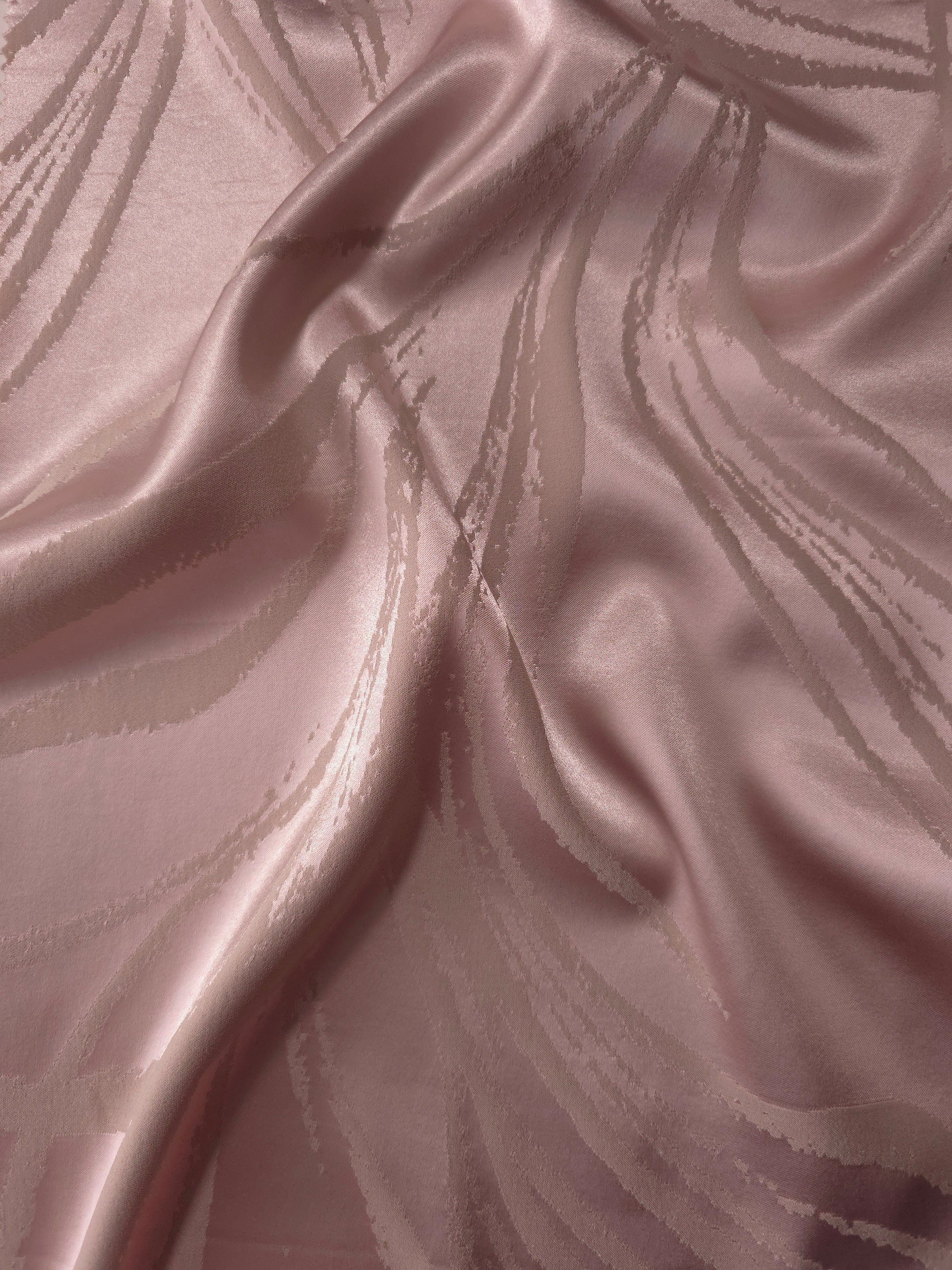 Dusty rose Lassi satin folded to show how the seaweed motif catches light differently across each curve