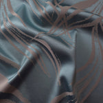 Slate blue satin folded over itself, with the mauve-toned seaweed lines crossing at different angles in the fold
