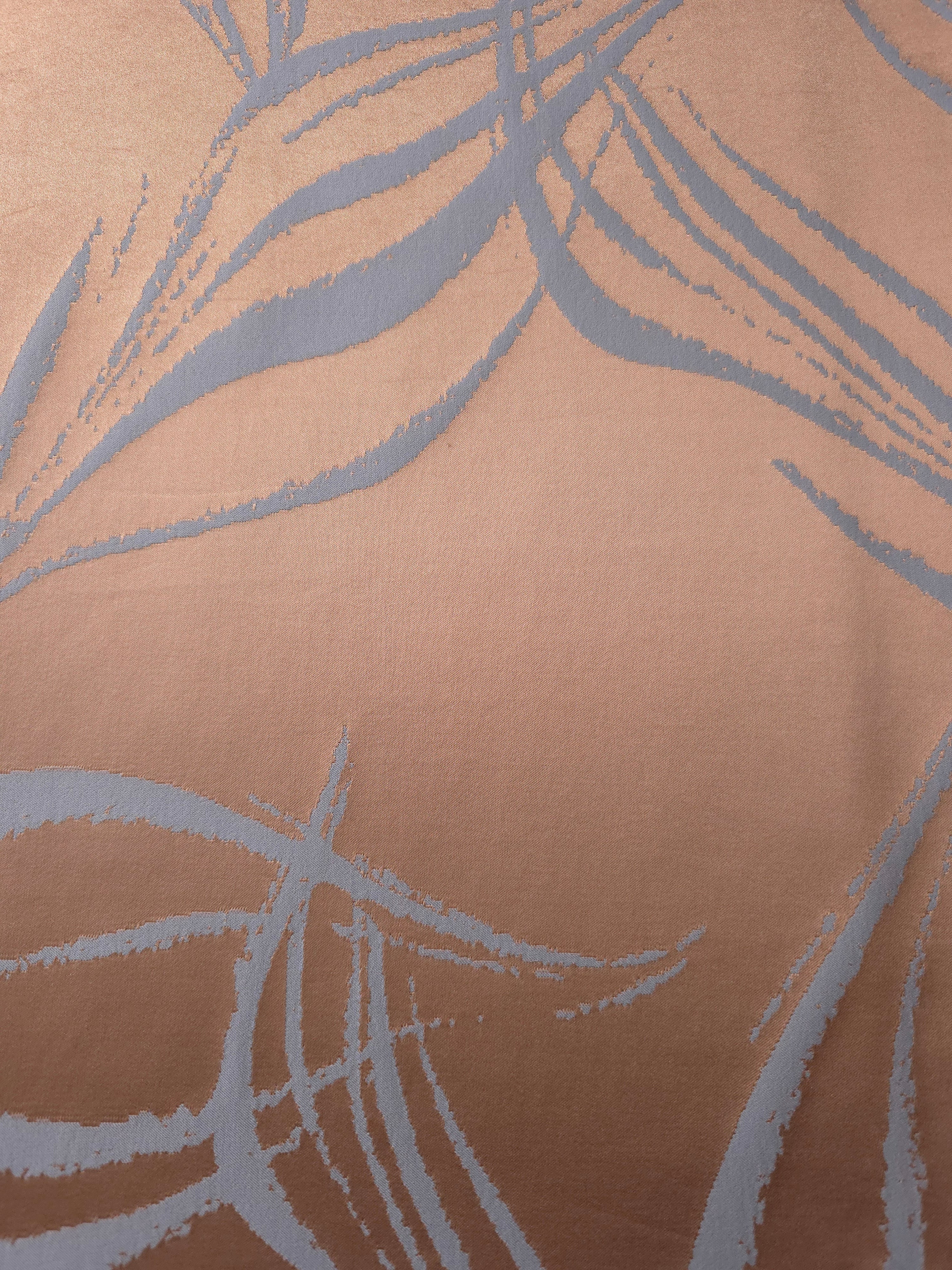 A wider view of the copper and blue-grey seaweed satin laid out, showing the full scale of the repeat