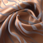 A tight fold in the copper satin, where the blue-grey wave lines bend sharply at the crease