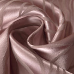 A soft fold in the mauve-plum satin, the wave pattern catching light unevenly across the crease