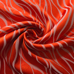 Orange-red Lassi satin draped to catch the light, the contrast lines clearly visible across the moving fabric