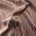 Copper Lassi satin folded over itself, the wave lines shifting between warm copper and cool blue-grey as the light moves