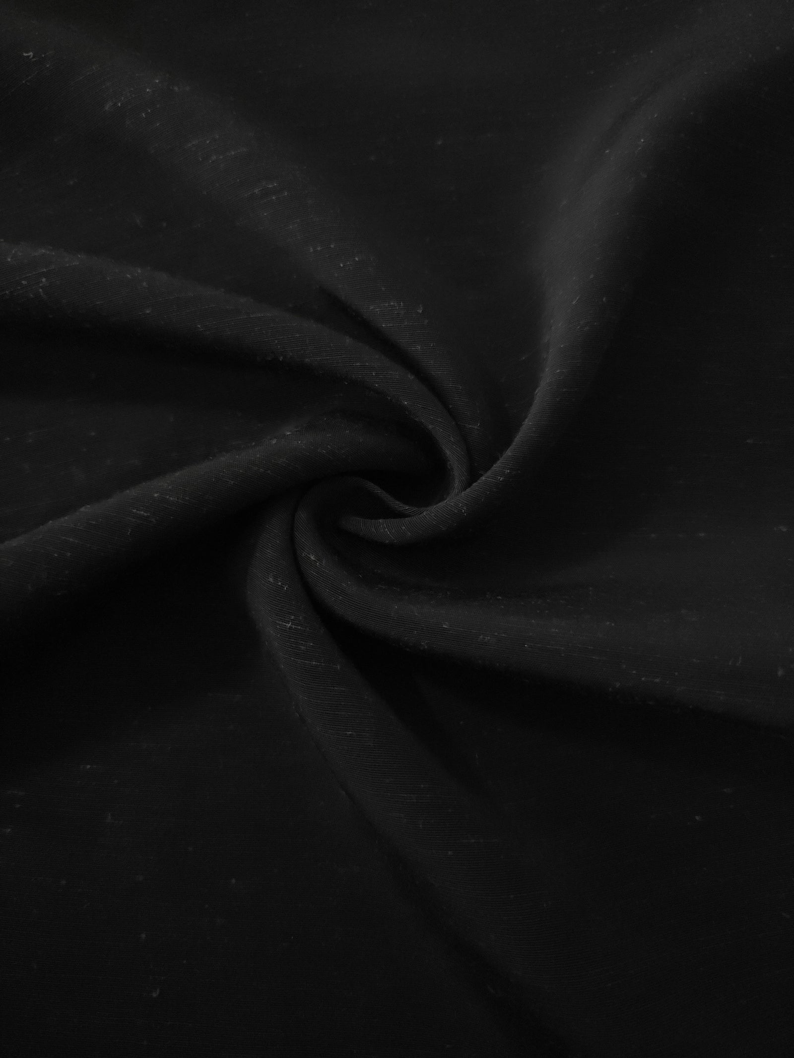 Deep black linen viscose plain fabric folded to show its lightweight, garment-ready texture.
