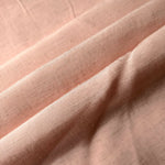 Folded delicate blush pink linen viscose plain fabric, illustrating its lightweight feel for garment sewing.