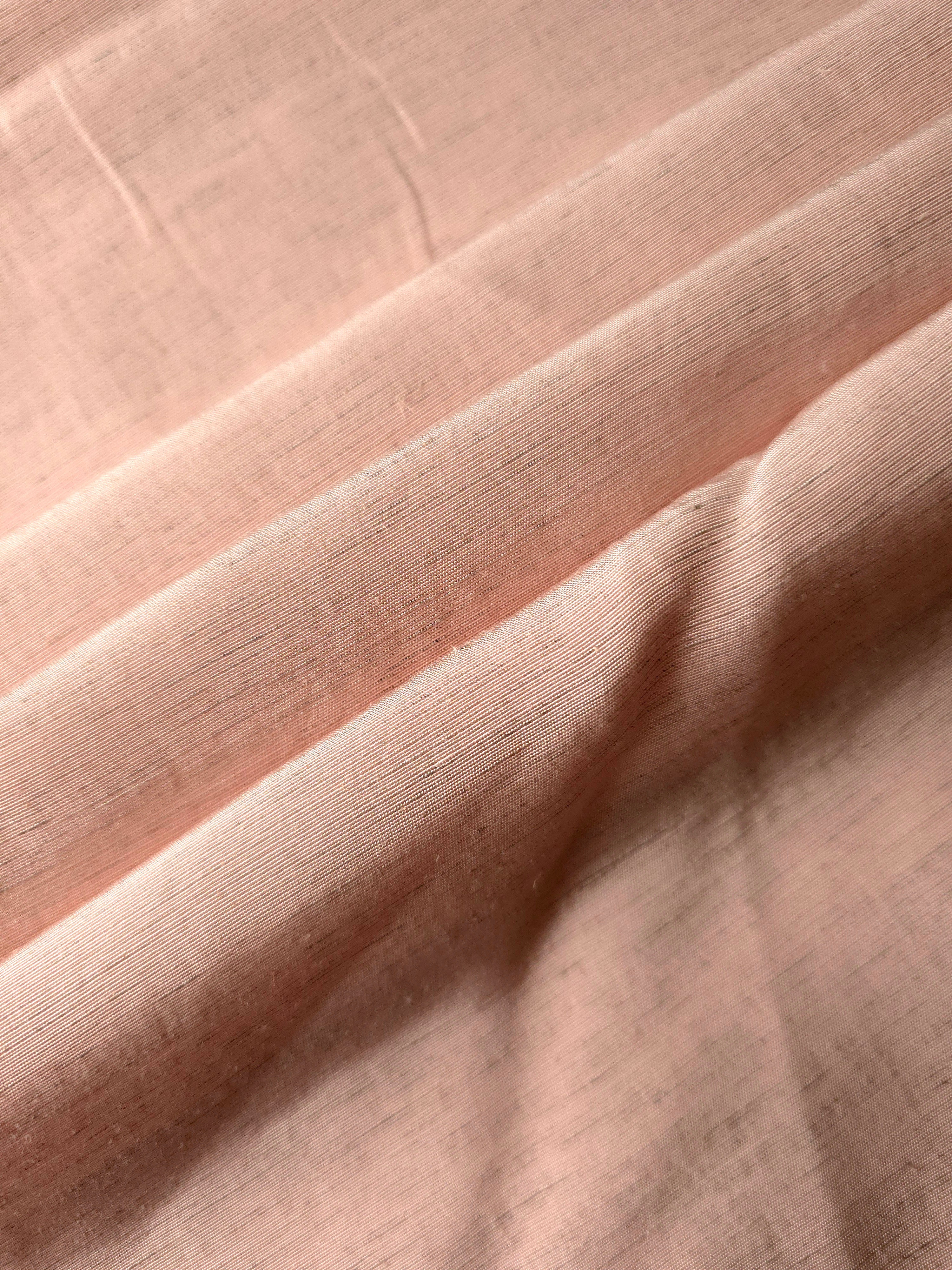 Folded delicate blush pink linen viscose plain fabric, illustrating its lightweight feel for garment sewing.
