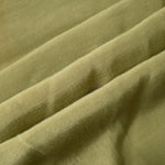 Fresh apple green linen viscose plain fabric folded to show its lightweight, garment-ready texture.
