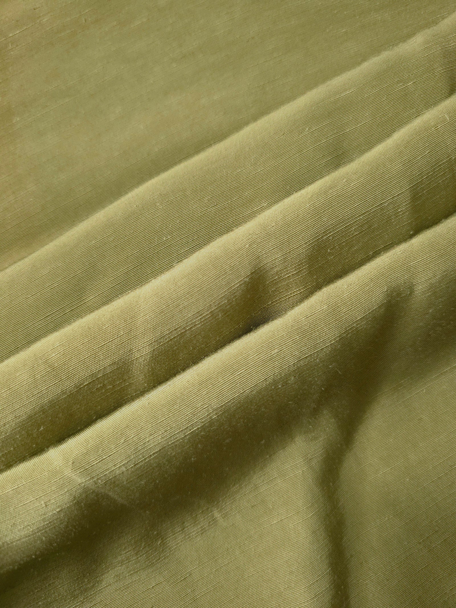 Fresh apple green linen viscose plain fabric folded to show its lightweight, garment-ready texture.