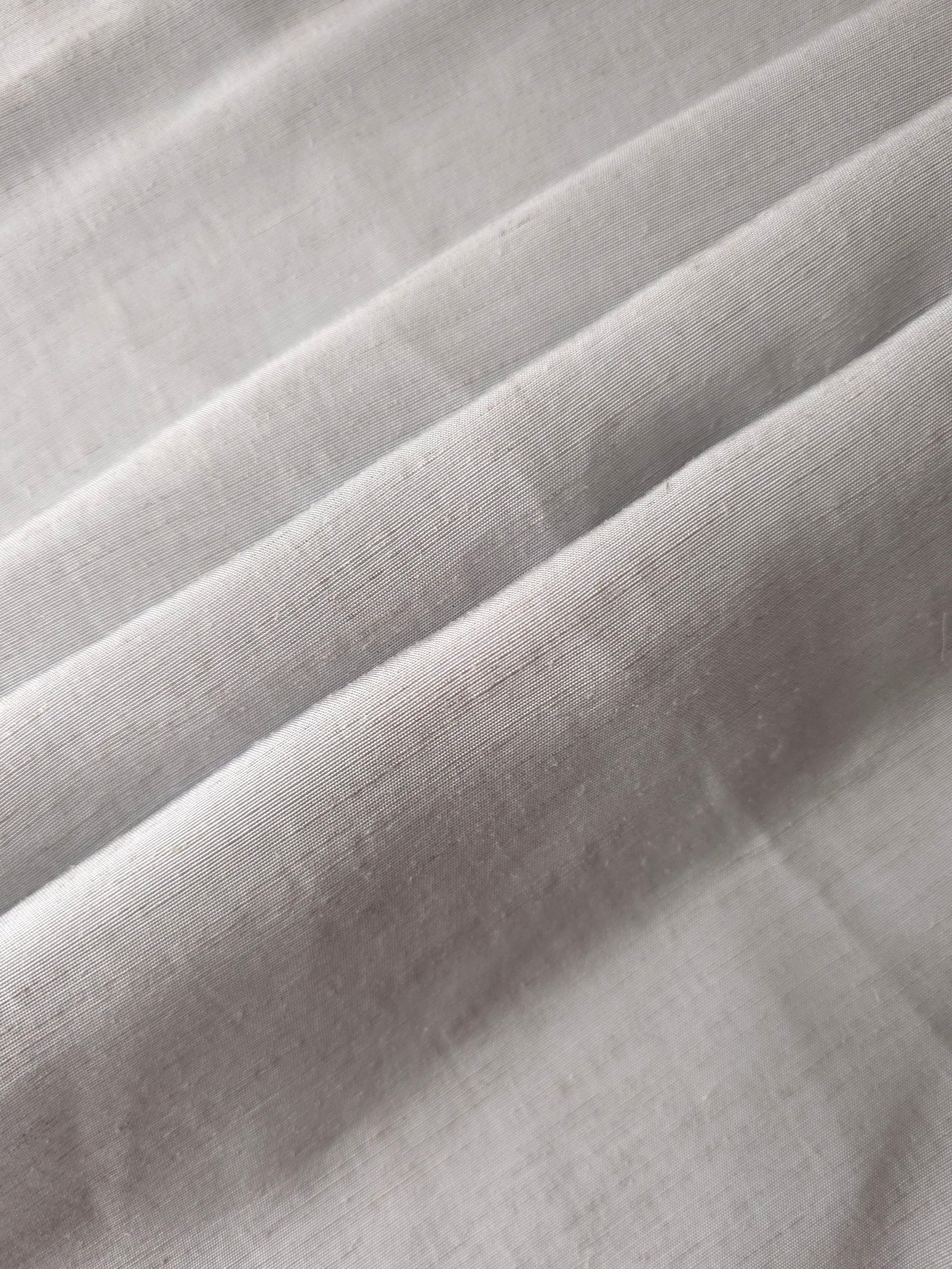 Soft pearl grey linen viscose plain fabric texture, showing the soft, flowy hand of the weave.