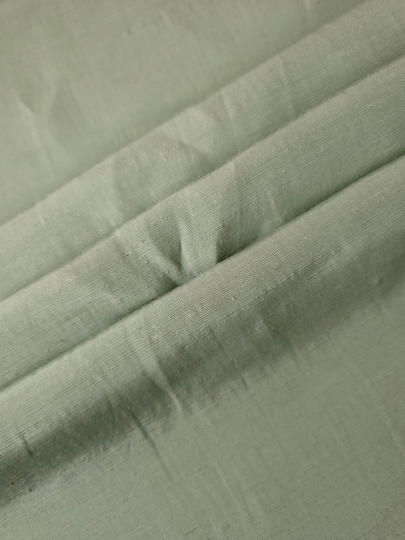 Texture view of muted sage grey linen viscose plain fabric highlighting its flowy, breathable finish.