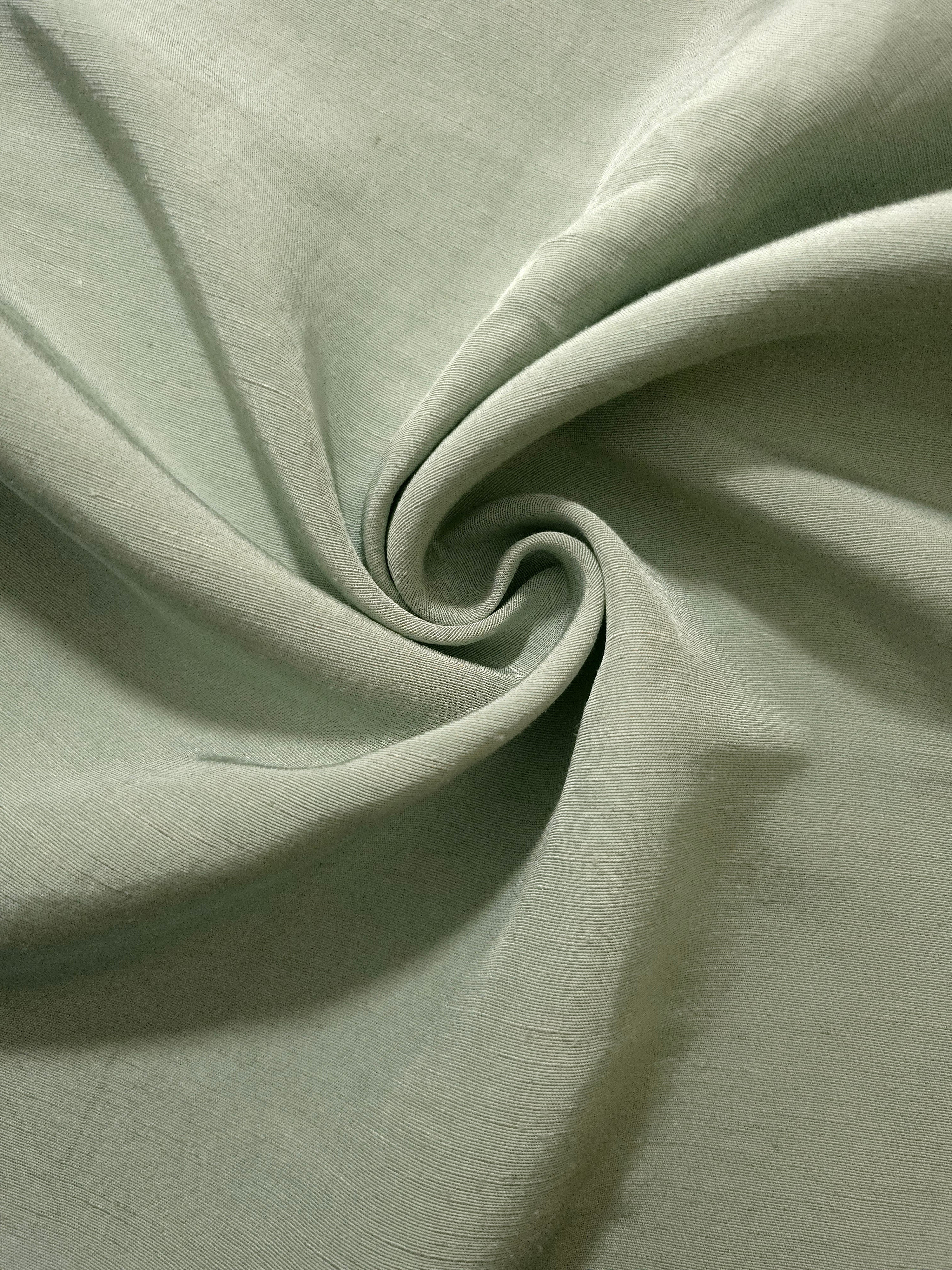 Muted sage grey linen viscose plain fabric folded to show its lightweight, garment-ready texture.