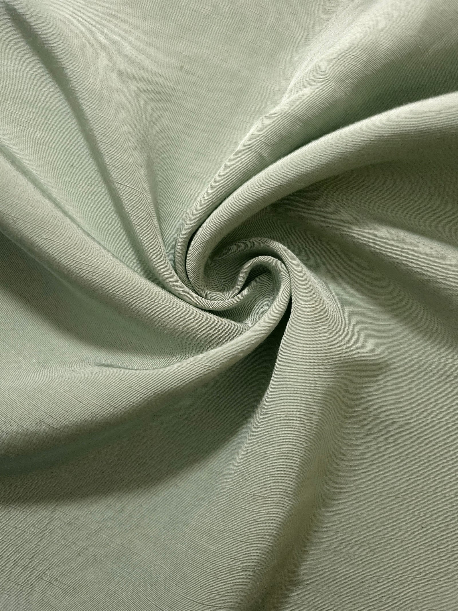Muted sage grey linen viscose plain fabric folded to show its lightweight, garment-ready texture.
