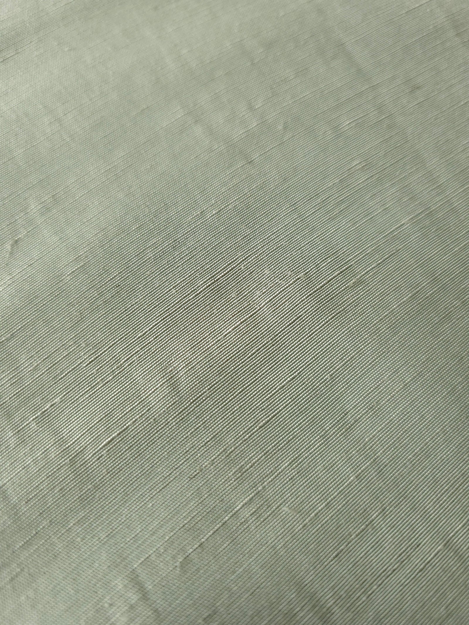 Muted sage grey linen viscose plain fabric draped to show its soft structure, ideal for dressmaking.