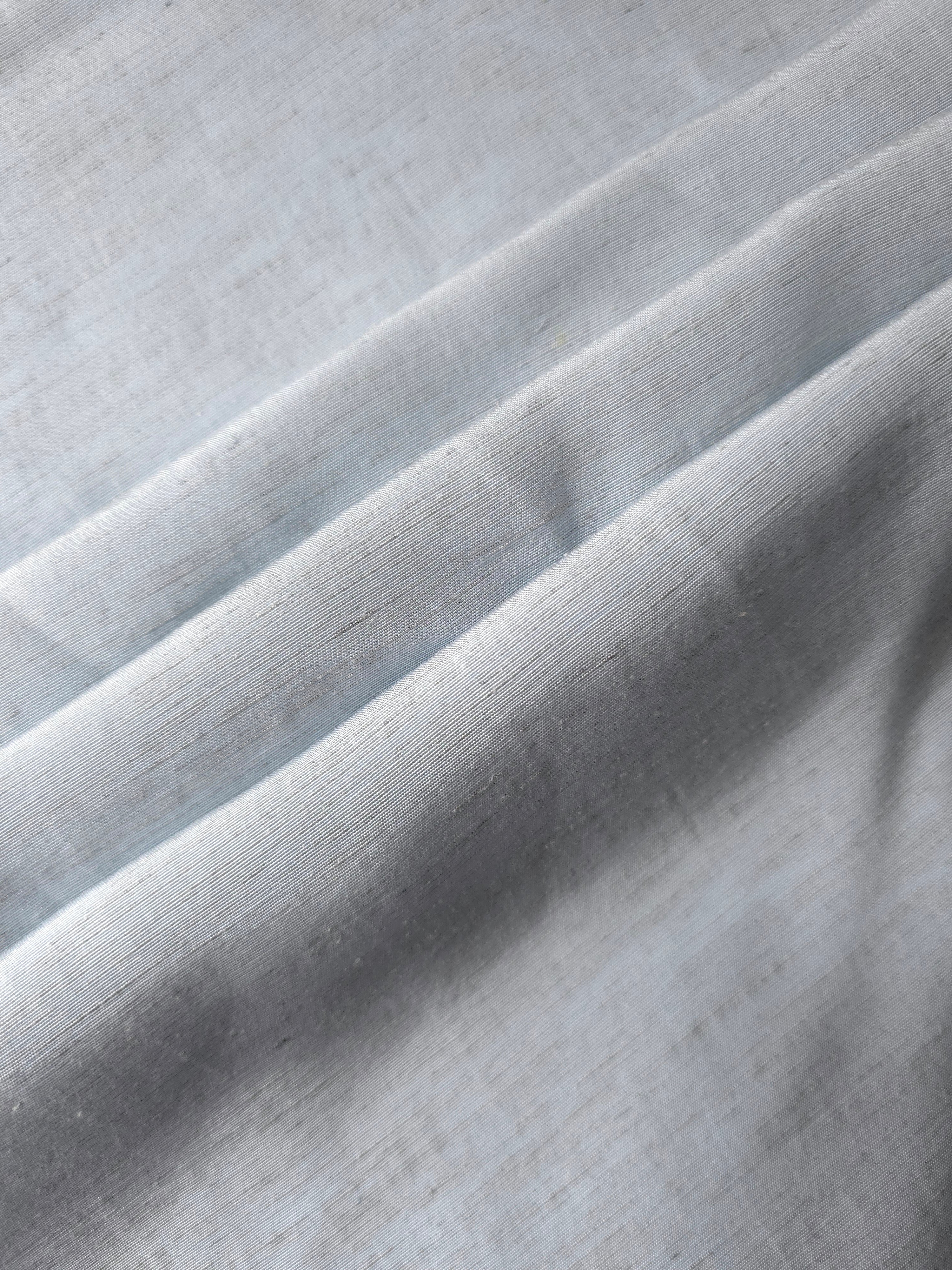 Cool grey-blue linen viscose plain fabric folded to show its lightweight, garment-ready texture.