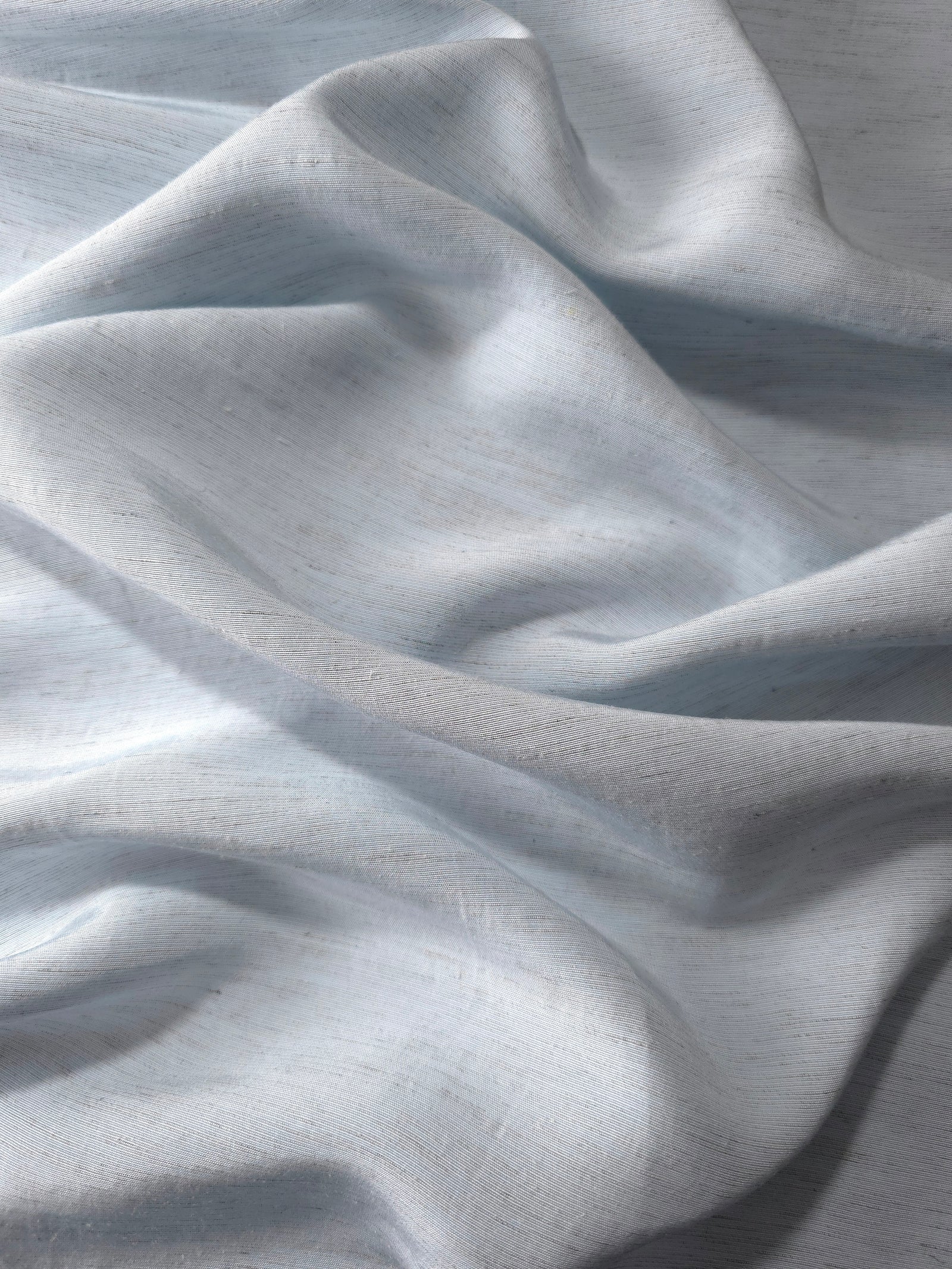 Close-up of cool grey-blue linen viscose plain fabric showing its natural woven texture.