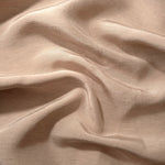 Texture view of warm sandy beige linen viscose plain fabric highlighting its flowy, breathable finish.