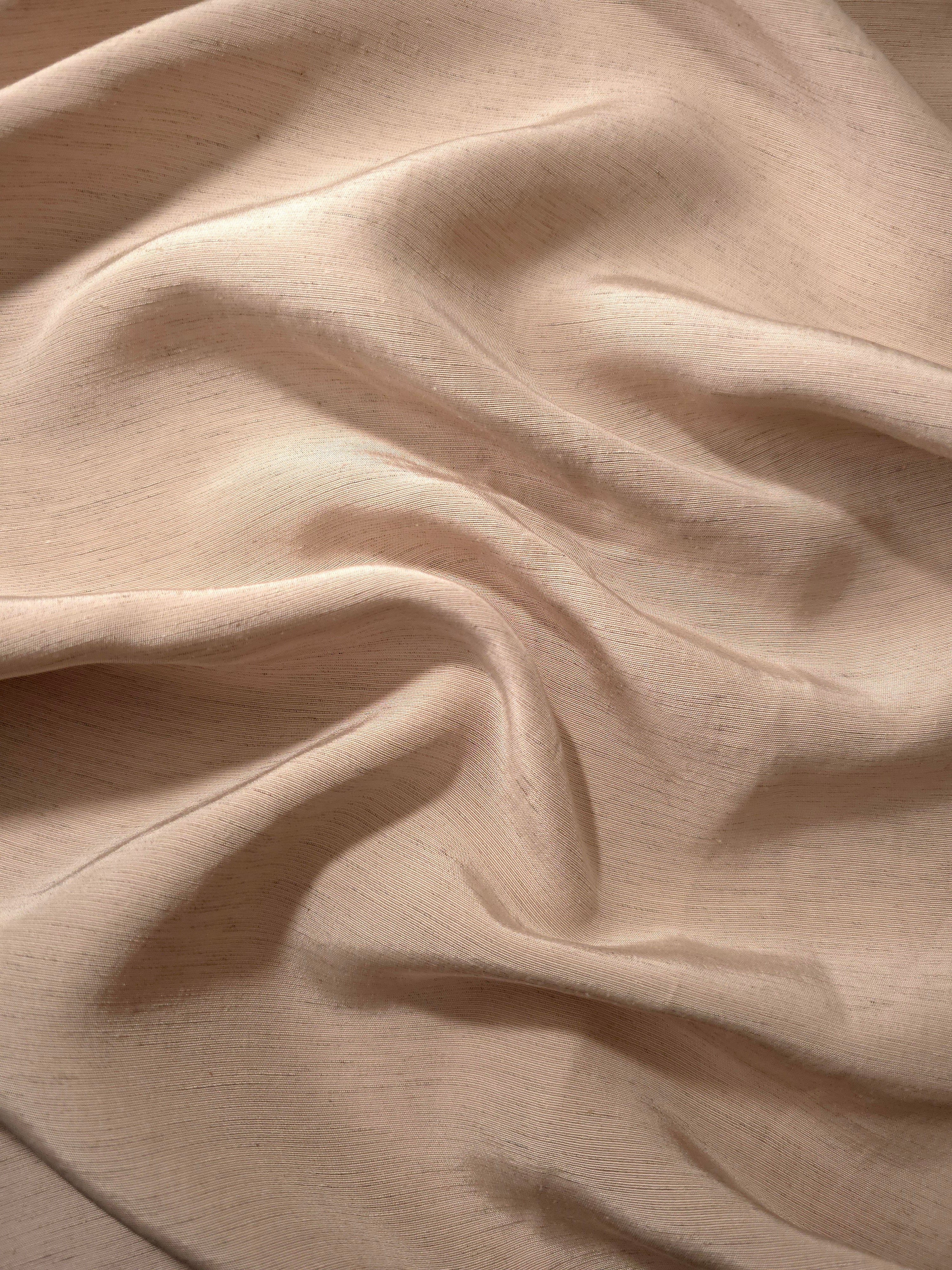 Texture view of warm sandy beige linen viscose plain fabric highlighting its flowy, breathable finish.