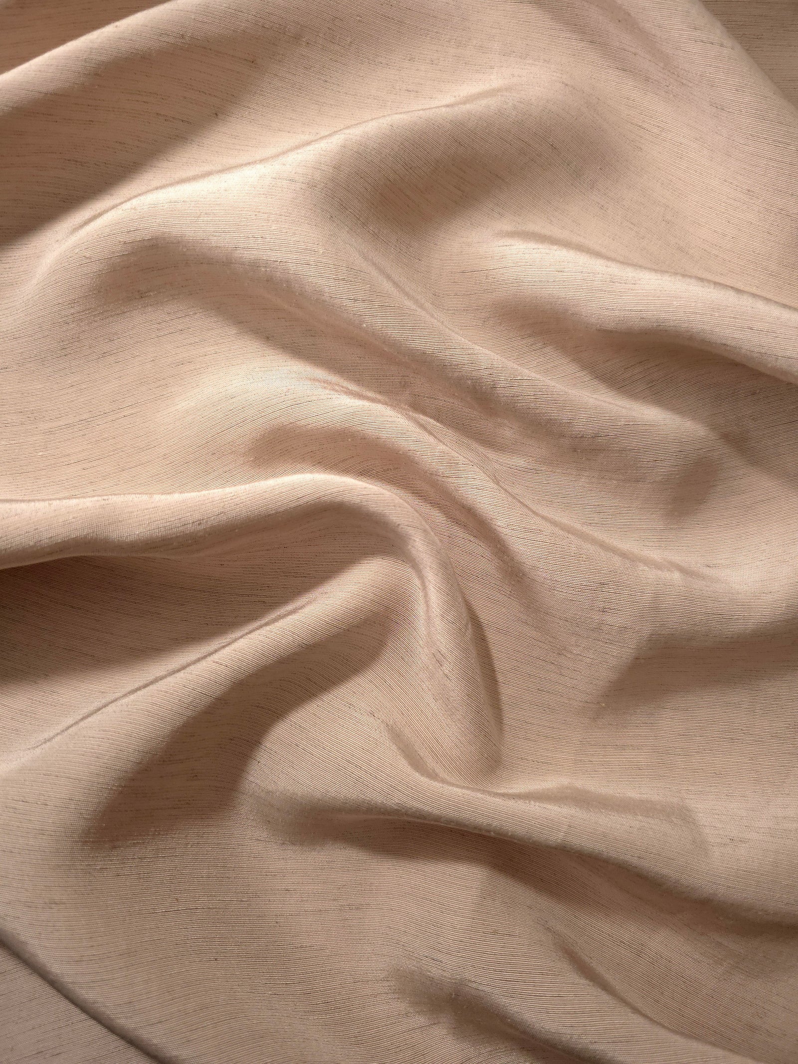 Texture view of warm sandy beige linen viscose plain fabric highlighting its flowy, breathable finish.