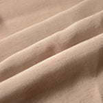 Warm sandy beige linen viscose plain fabric folded to show its lightweight, garment-ready texture.