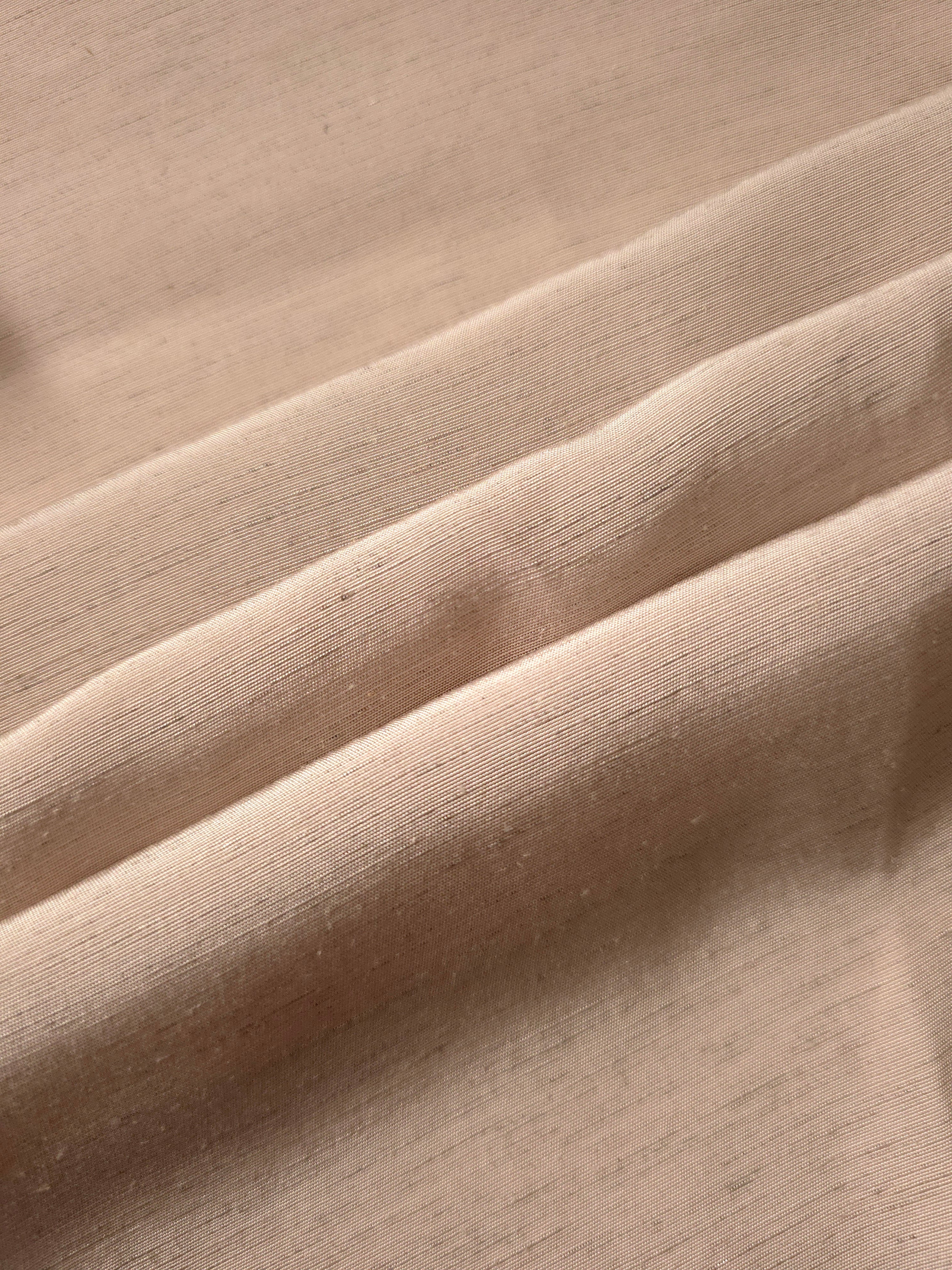 Warm sandy beige linen viscose plain fabric folded to show its lightweight, garment-ready texture.