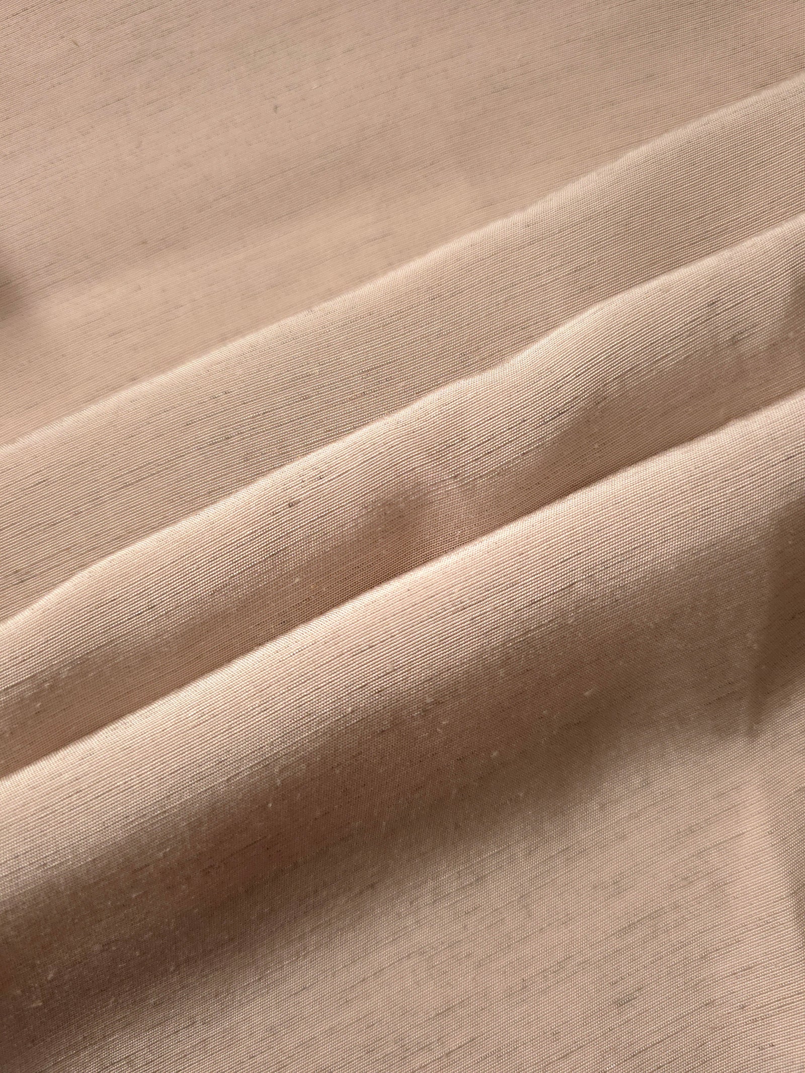 Warm sandy beige linen viscose plain fabric folded to show its lightweight, garment-ready texture.