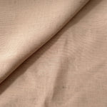 Close-up of warm sandy beige linen viscose plain fabric showing its natural woven texture.