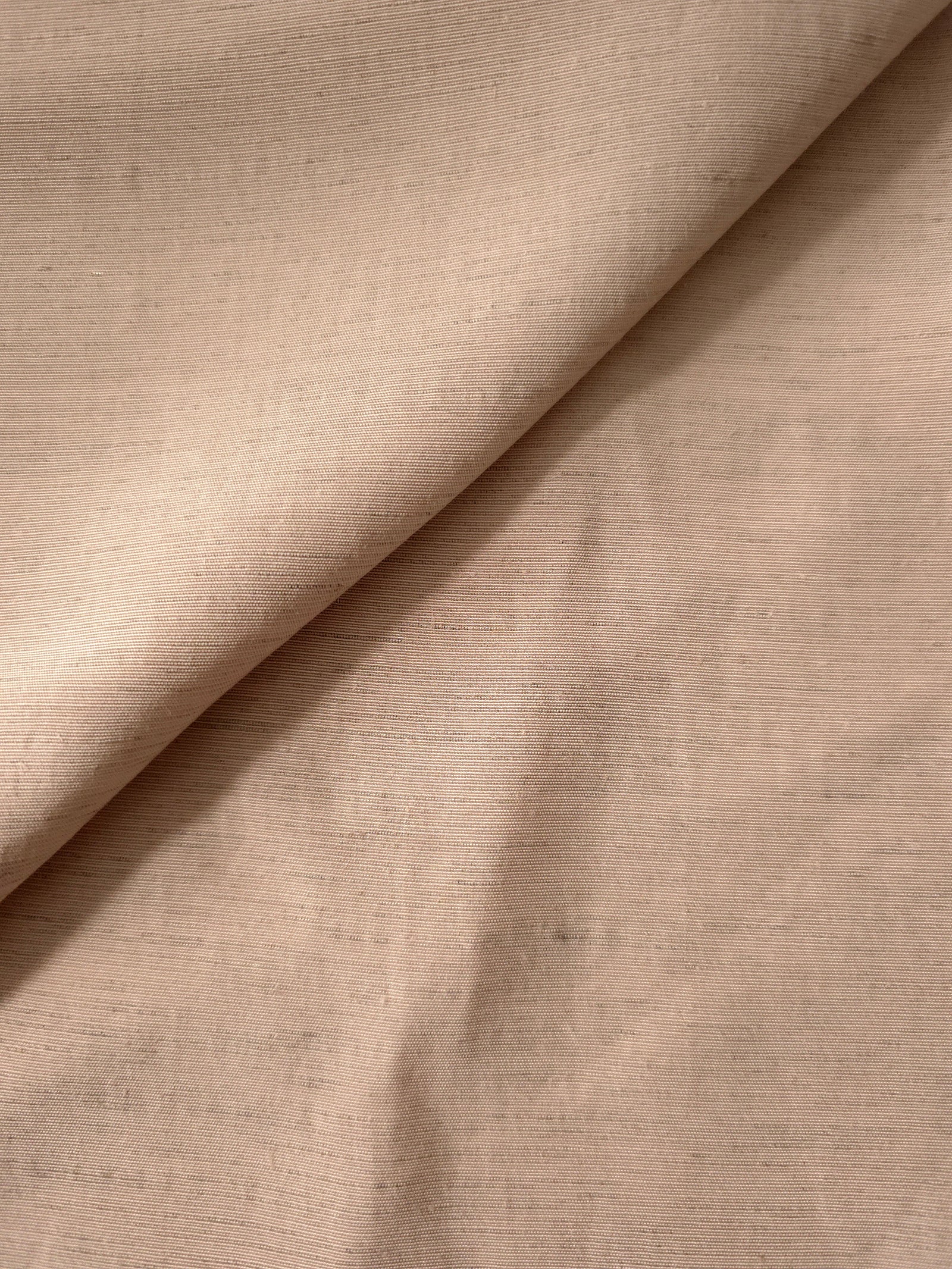 Close-up of warm sandy beige linen viscose plain fabric showing its natural woven texture.