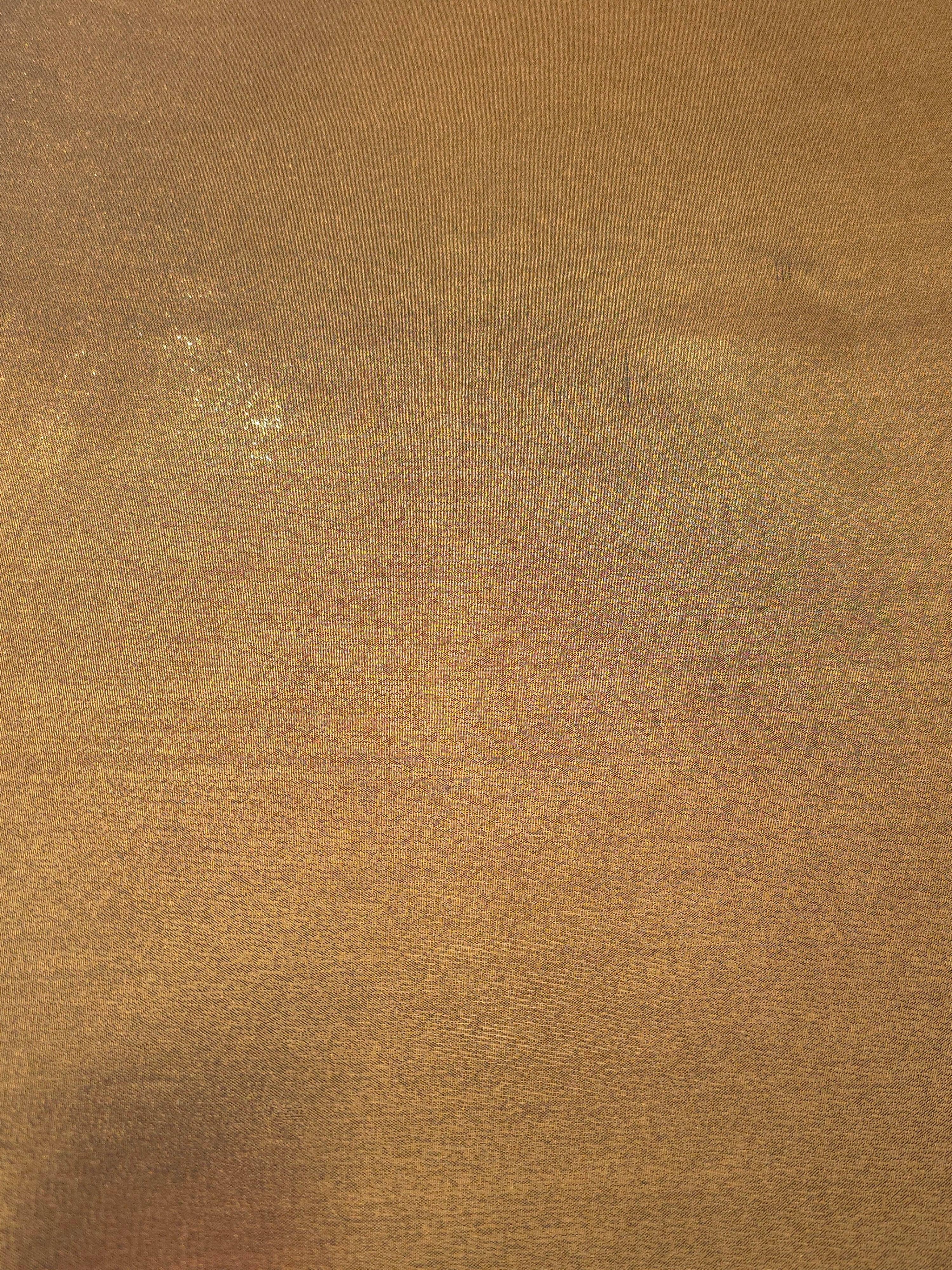 Antique brass fabric overview view of liquid metallic shimmer chiffon fabric, highlighting fluid folds and reflective surface